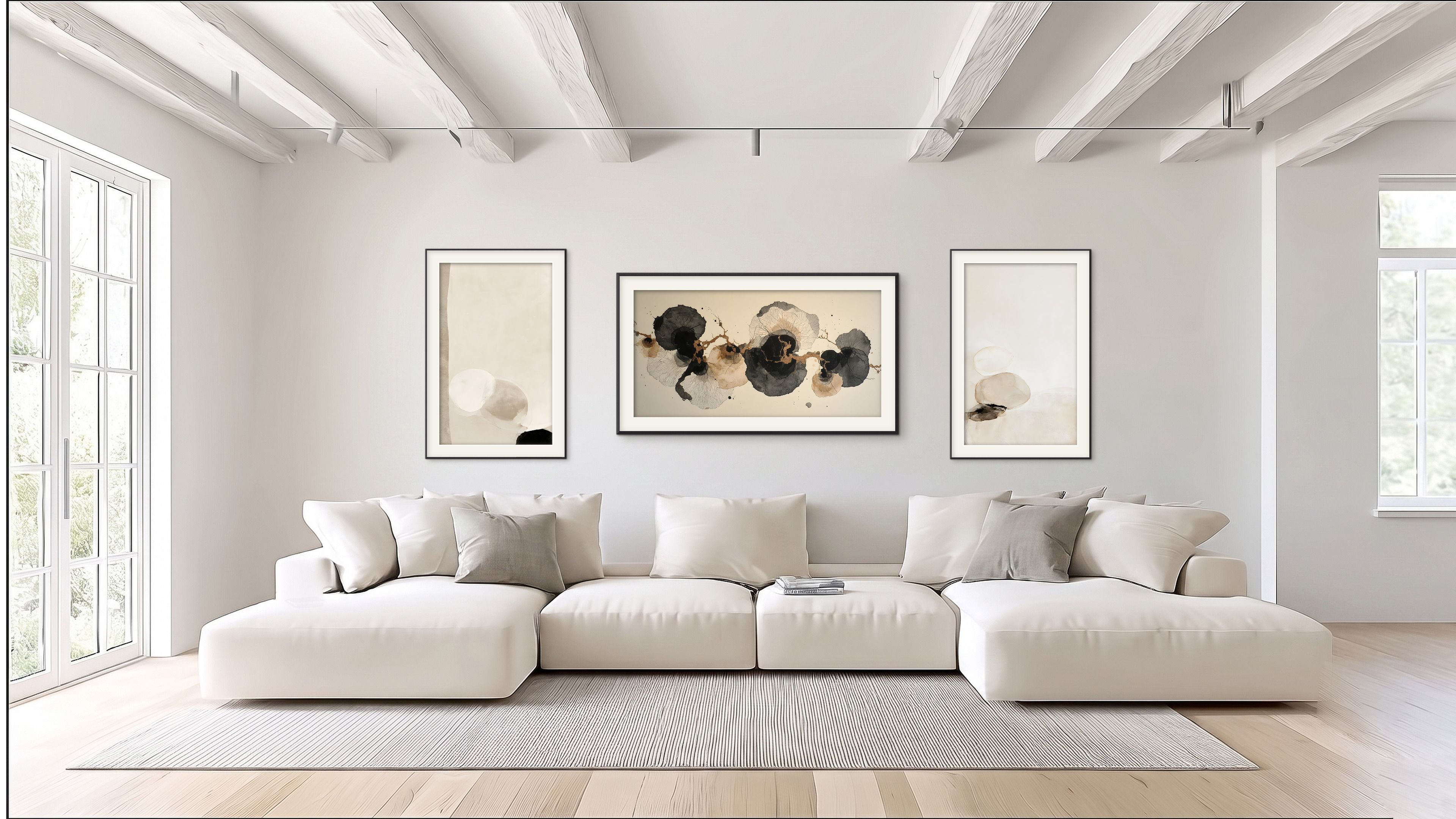 Three Soft Structure abstract artworks in cream, beige, black, and warm earth tones displayed above a large white sofa in a bright modern living room.